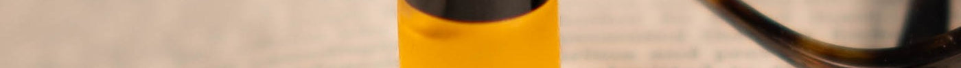 Oud rollerball on an open book beside reading glasses