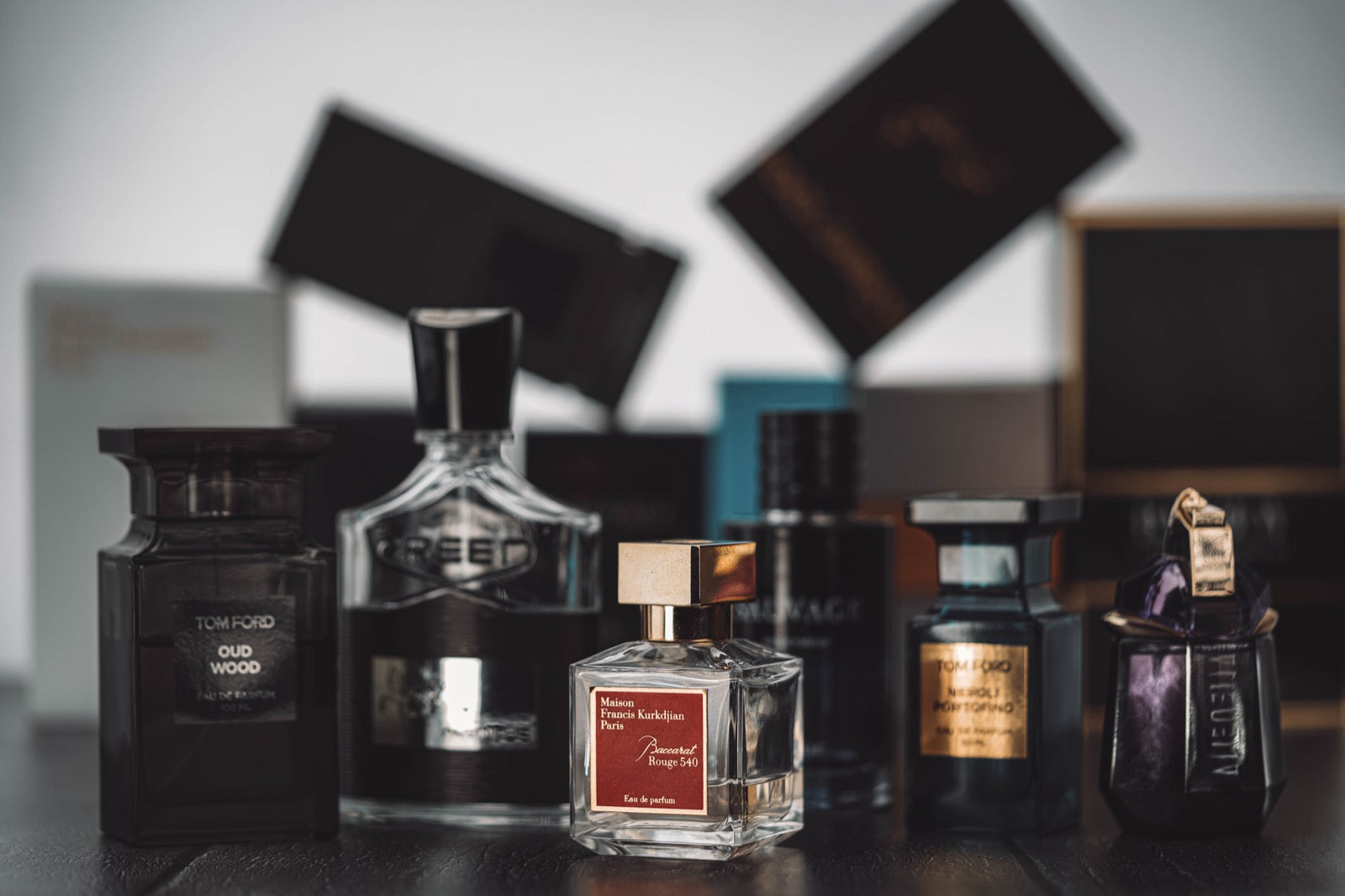 Classic designer perfume bottles lined up on a dark table