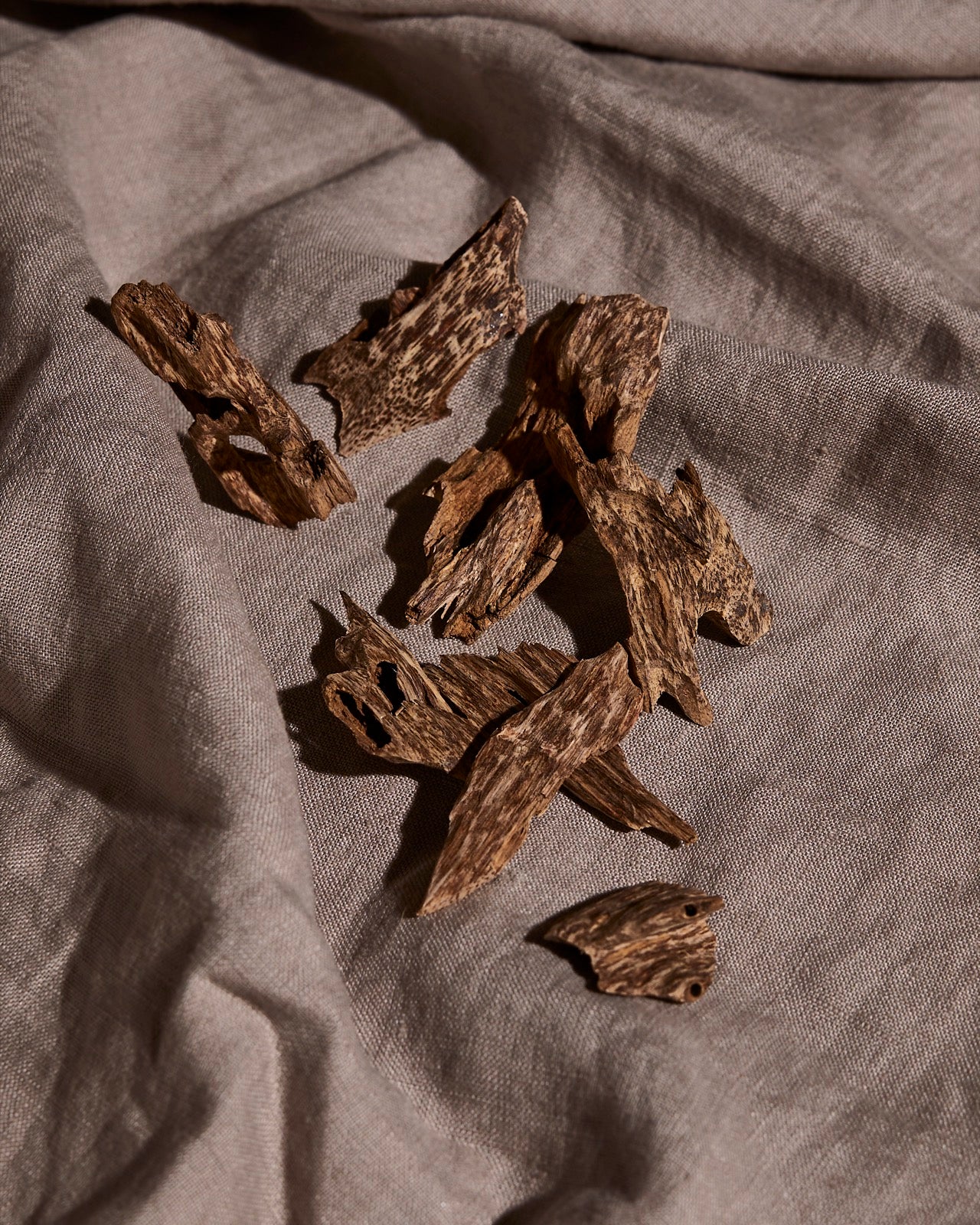 Agarwood oud chips on grey linen in warm light