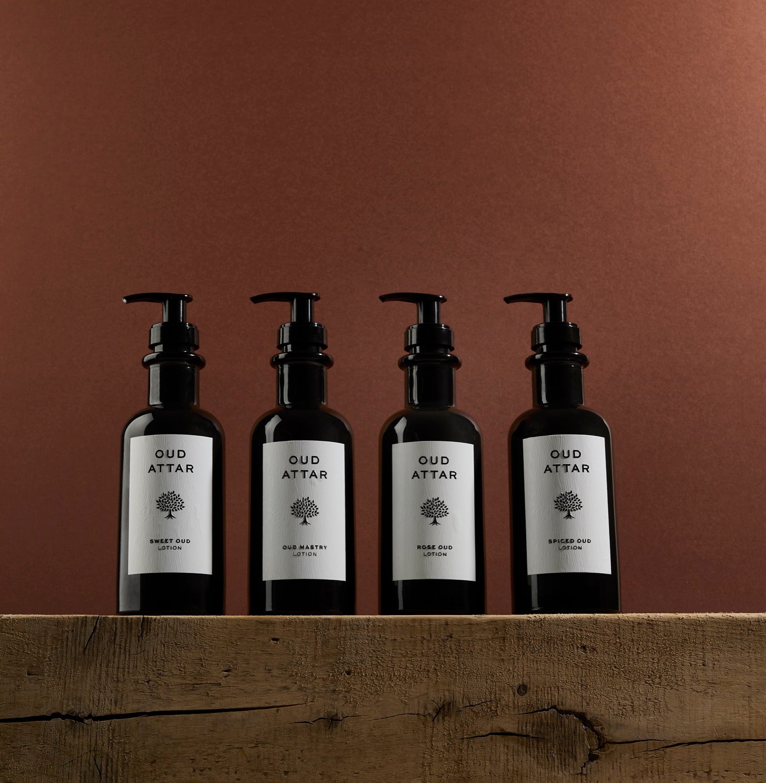 Four Oud Attar lotions lined up on rustic wood