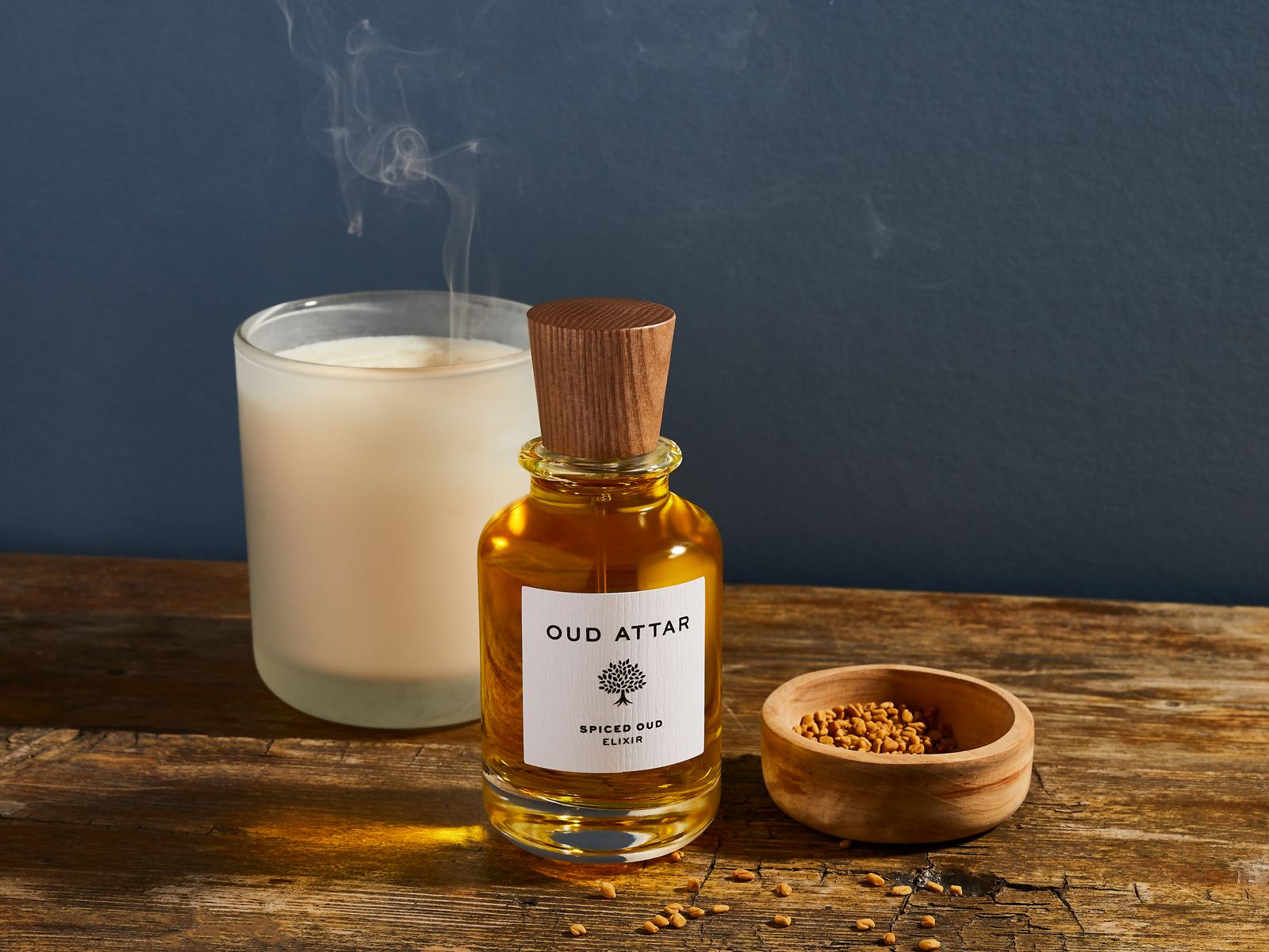 Spiced Oud elixir beside a candle on a wooden table
