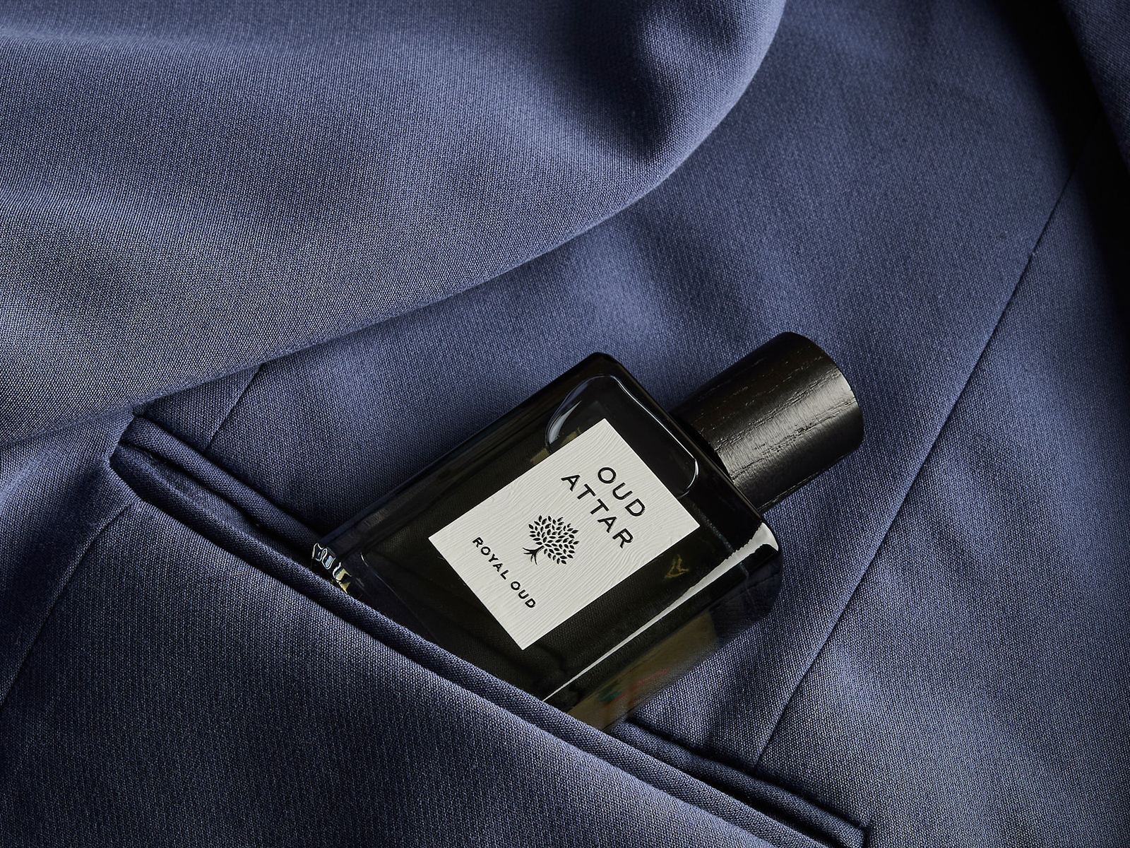 Royal Oud perfume oil tucked into the pocket of a navy jacket
