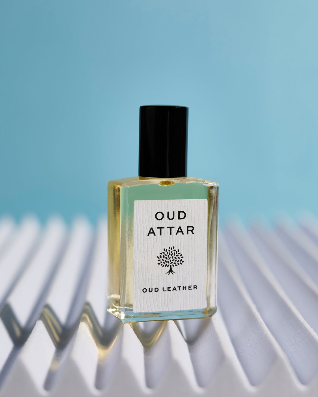 Oud Leather bottle on white pleats against sky blue