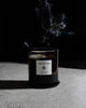 Vanilla Oud candle with smoke wisps on a dark backdrop
